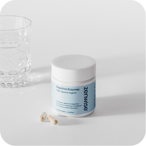 White jar of Zenwise Digestive Enzymes supplement with blue label next to scattered capsules and crystal glass on white surface