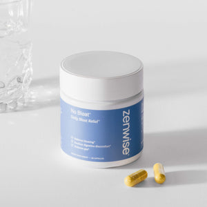 White and blue Zenwise No Bloat supplement bottle with two yellow capsules beside it on white surface